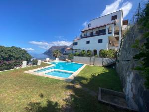 a villa with a swimming pool in front of a house at Gigantes Cliff Holiday Home by Sydney Playa Sur in Acantilado de los Gigantes
