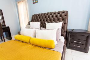 a bed with yellow pillows and a brown headboard at The Hide on kilburn in Roodepoort