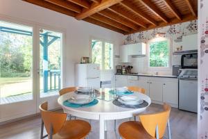 een witte keuken met een witte tafel en stoelen bij Le Chalet à la Mer in Erdeven