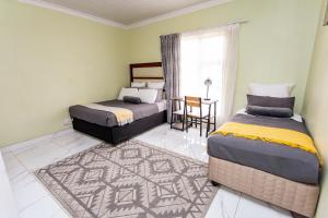 a bedroom with two beds and a table and a window at The Hide on kilburn in Roodepoort