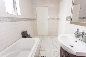 a white bathroom with a tub and a sink at The Hide on kilburn in Roodepoort