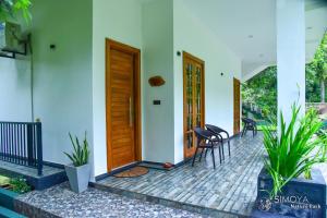 un porche delantero de una casa con puerta de madera en Simoya Nature Park en Dambulla