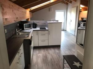 a kitchen with white cabinets and a sink and microwave at Ferienwohnung am Freibad in Schwarzach