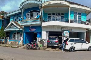 a man standing next to a car and a motorcycle in front of a building at Arjuna 2 Homestay Syariah Dieng in Diyeng