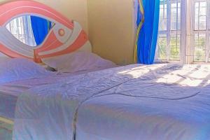 a bed with a blue comforter and a large window at Arjuna 2 Homestay Syariah Dieng in Diyeng