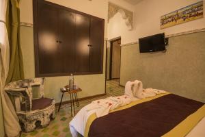 a bedroom with a bed and a chair and a tv at Riad Les Oliviers & Spa in Marrakech