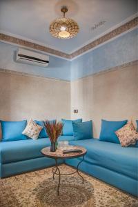 a living room with a blue couch and a table at Riad Les Oliviers & Spa in Marrakesh