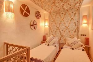 two beds in a room with a wall at Riad Les Oliviers & Spa in Marrakesh