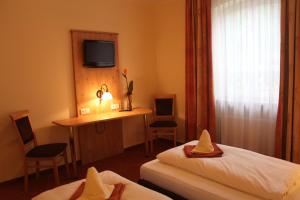 una camera d'albergo con 2 letti, una scrivania e una TV di Landgasthof Ostermair a Petershausen