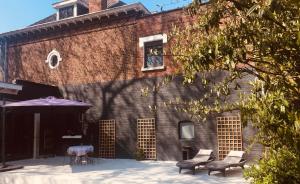 - un bâtiment en briques avec des chaises et une table devant dans l'établissement La Villa des Roses - Suite & Spa, à Lys-lès-Lannoy
