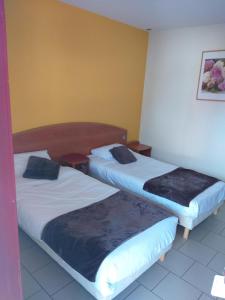 2 Betten in einem Hotelzimmer mit Röcken in der Unterkunft LOGIS Hôtel - Les Paturelles in Avesnelles