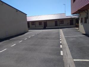 an empty parking lot with two buildings and a blue sky at LOGIS Hôtel - Les Paturelles in Avesnelles