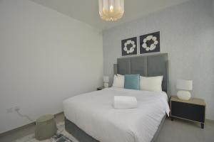 a bedroom with a large white bed and a lamp at bnbmehomes - Elegant 3 BR - Dubai South - G04 in Dubai