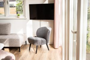 a bedroom with a chair and a bed and a television at Het Mienterbos in De Koog