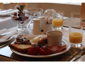 een bord met ontbijtproducten op een tafel met sinaasappelsap bij Athol House in Filey