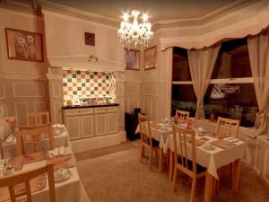 een eetkamer met tafels en stoelen en een kroonluchter bij Athol House in Filey