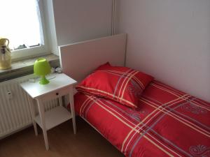 niewielka sypialnia z czerwonym łóżkiem i stołem w obiekcie White House Bochum Ehrenfeld w mieście Bochum