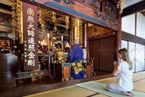 a girl sitting in front of a priest in a temple at 宿坊 観音院 Temple Hotel Kannonin in Kiryu