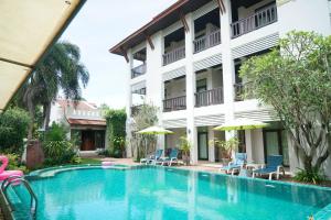 a pool in front of a building with chairs and umbrellas at Monaburi Boutique Resort in Rawai Beach