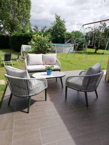 a patio with two chairs and a couch and a table at Chambre privée calme,campagne, piscine,étape,déplacement pro,abri moto vélo,parking in Vaux-sur-Vienne