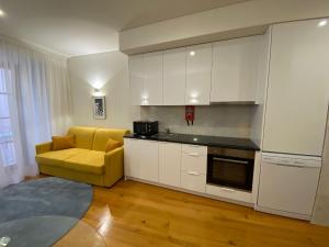 a kitchen with white cabinets and a yellow couch at TM Luxury Apartments Lisbon in Lisbon