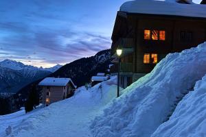 リーダーアルプにあるChumma Duplexの雪の丘の上の明かりのついた建物