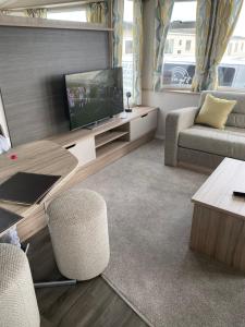 uma sala de estar com uma televisão e um sofá em 77 The Brambles em Porthcawl
