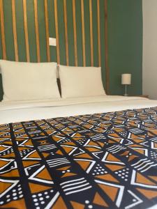 a bedroom with a bed with an orange and black comforter at LA VILLA M in Conakry