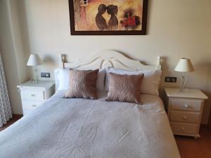um quarto com uma cama branca com duas mesas de cabeceira em Apartamentos Nordés2 em Malpica de Bergantiños