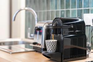 una macchinetta del caffè seduta su un bancone della cucina con una tazza di Frontière de Monaco - Studio rénové - AE a Beausoleil