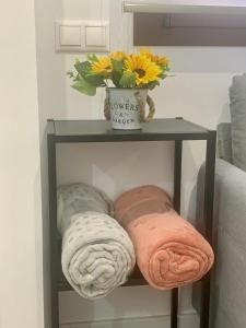 a shelf with towels and a vase of flowers on it at Puerta de Caceres Apartamento 5 Callejón De Don Álvaro in Cáceres