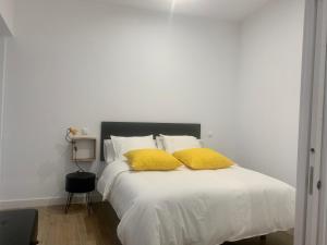 a bedroom with a white bed with yellow pillows at Puerta de Caceres Apartamento 5 Callejón De Don Álvaro in Cáceres