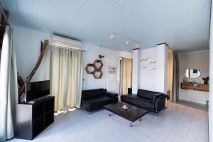Sala de estar con 2 sillas negras y TV en LefkasLoft, en Lefkada