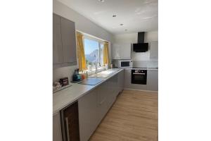 a kitchen with white cabinets and a counter top at Deu Draeth in Abersoch