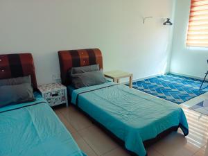 een slaapkamer met 2 bedden, een tafel en een raam bij Homestay DTepian Bayu Bandar Seri Impian Kluang in Kluang