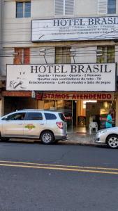 two cars parked in front of a hotel branch at Hotel Brasil in Presidente Prudente