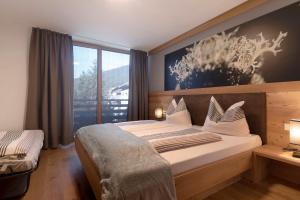 a bedroom with a large bed and a large window at Noreia Granda in Ortisei