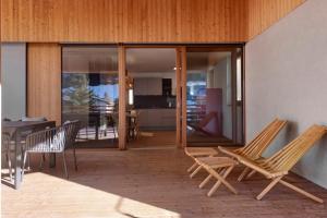 a patio with two chairs and a table and glass doors at Noreia Granda in Ortisei