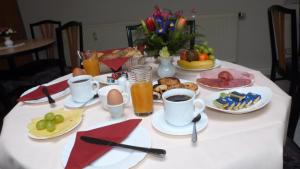 einen Tisch mit Teller mit Speisen und Tassen Kaffee in der Unterkunft Pension an der Weisseritz in Dresden