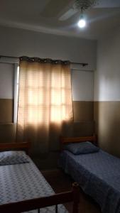 a bedroom with two beds and a window with a curtain at Hotel Brasil in Presidente Prudente