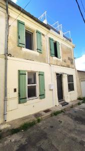 un viejo edificio blanco con persianas verdes. en Chambres tranquilles proche centre ville, en Arles