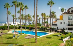 vista para a piscina do resort com palmeiras em Frontline Beach Apartment Marina Real 5009 em Manilva