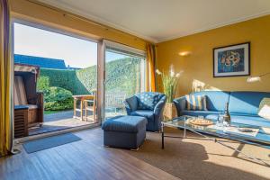 a living room with a blue couch and a glass table at Schallers Hüs 1 in Tinnum