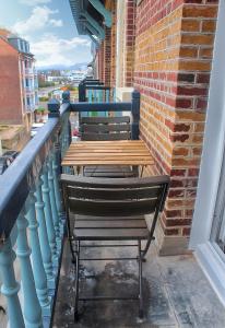 2 bancos de madera en un balcón con una pared de ladrillo en Le 8 ∙ Appartement cosy avec balcon vue sur mer, en Mers-les-Bains