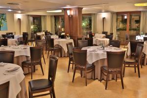 a dining room with tables and chairs with white tablecloths at Artemis Hotel in Cefalù