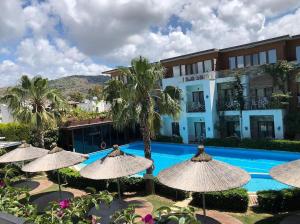 a resort with a pool and umbrellas and a building at Liona Hotel & SPA in Gundogan