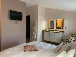 - une chambre avec un grand lit blanc et un lavabo dans l'établissement Gîte Orget, à Saint-Macaire