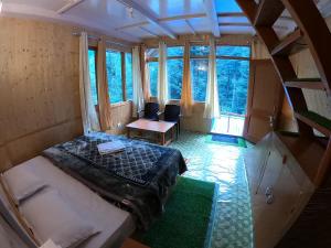 einen Blick über ein Schlafzimmer mit einem Bett und einem Tisch in der Unterkunft Reverberate Cafe & Cottages - Negi's Place in Jibhi