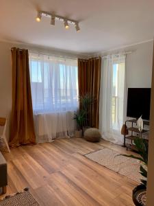 a living room with wooden floors and large windows at Katowice City Centre II in Katowice