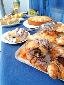 a blue table topped with plates of pastries and pies at Alba Chiara B&B in San Vito lo Capo